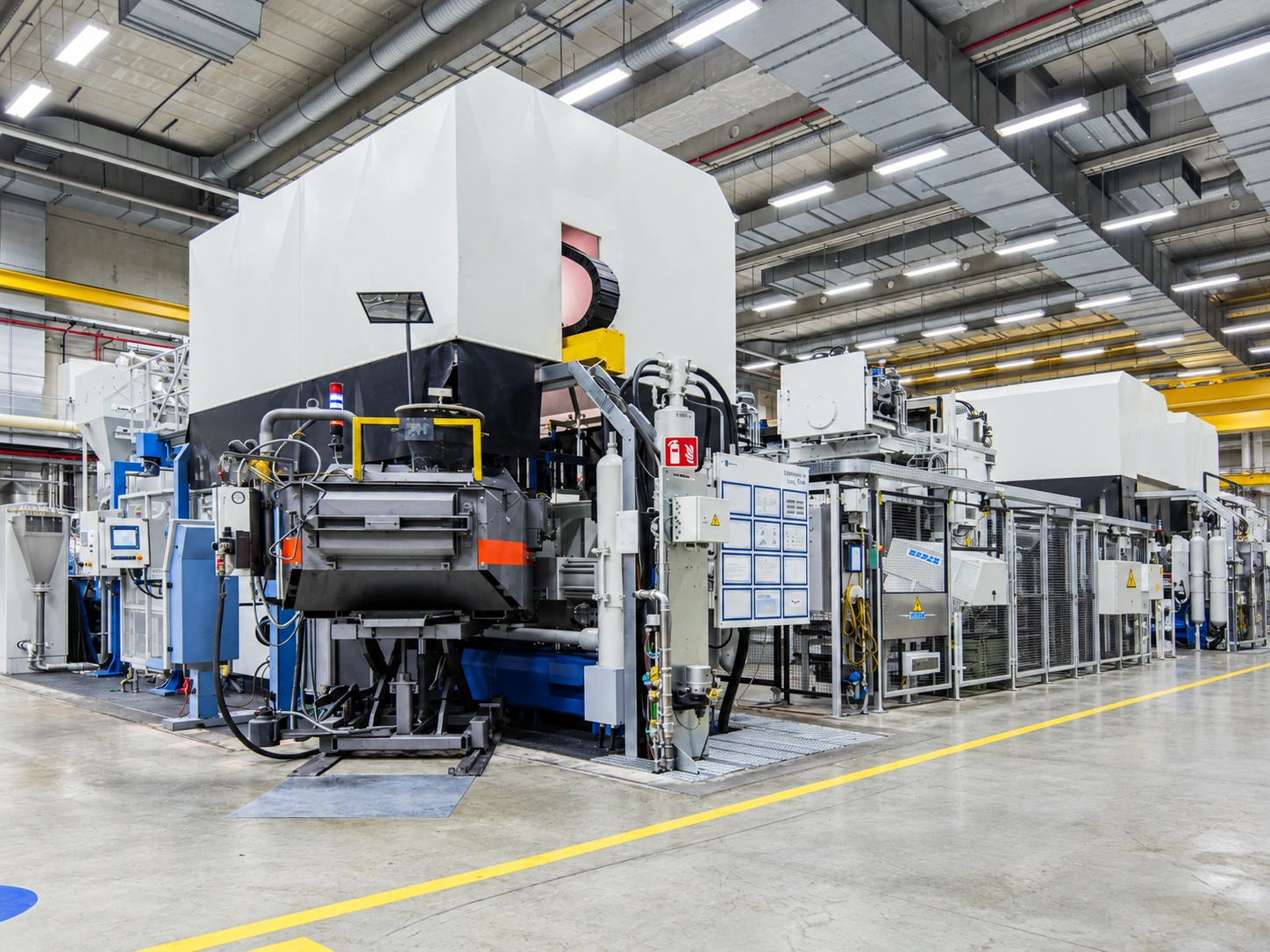 Illustrative die casting cell with surrounding equipment and protective fencing.